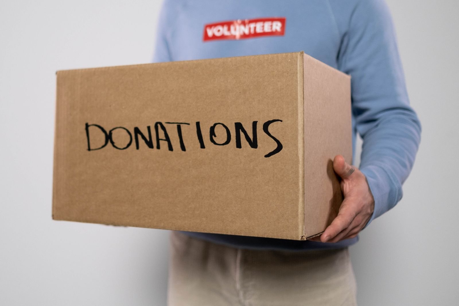 A volunteer smiling while carrying a box labelled donations