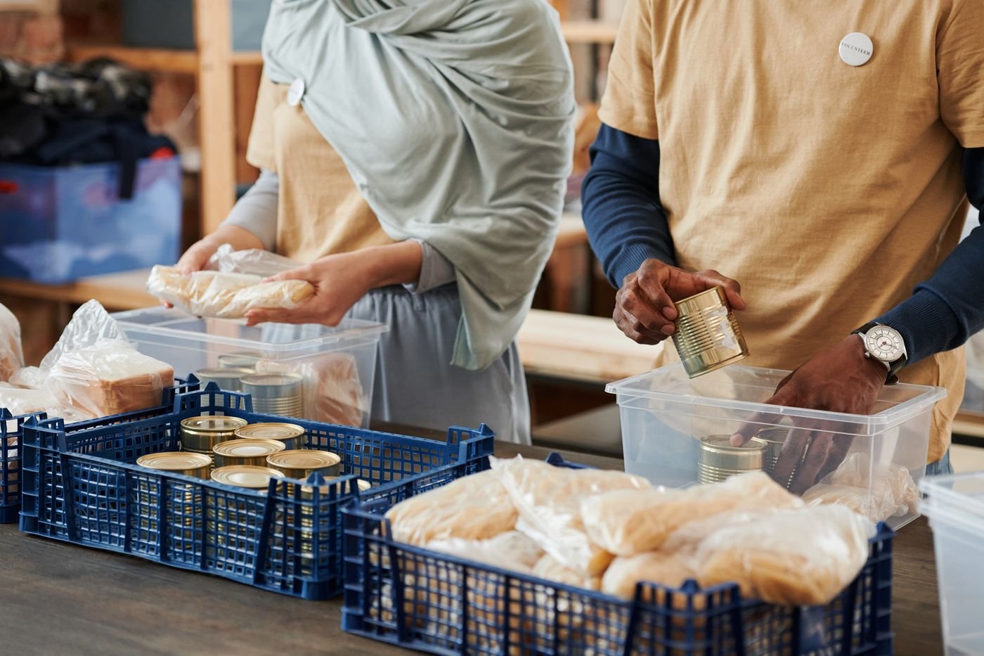 Two volunteers sorting food donations into crates at a community centre